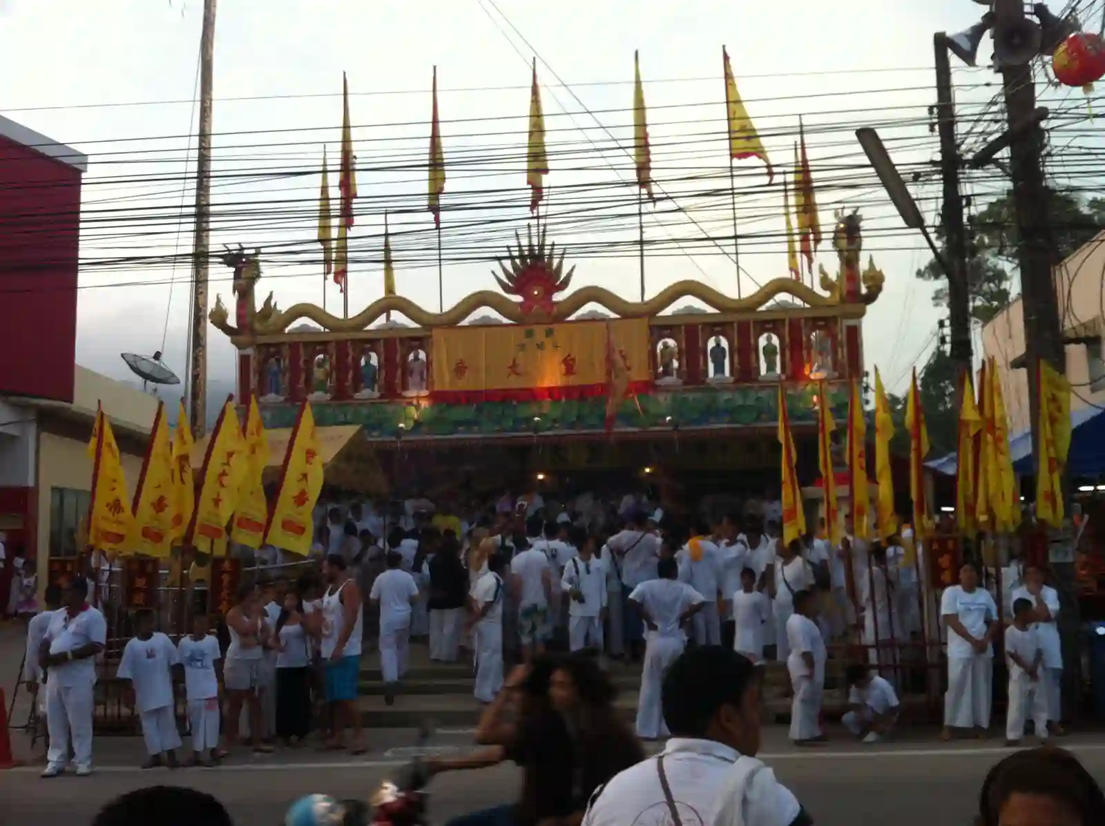 Santuario cinese con bandiere gialle del festival vegetariano e devoti in abiti bianchi a Phuket, in Thailandia