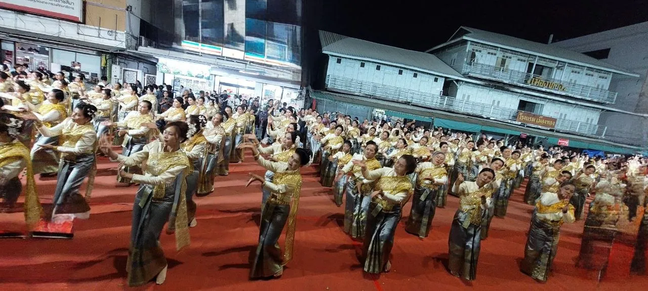 Una grande danza tradizionale isan in piazza di notte: decine di ballerine in costume dorato e verde scuro si muovono all'unisono sul tappeto rosso, nel nord-est della Thailandia