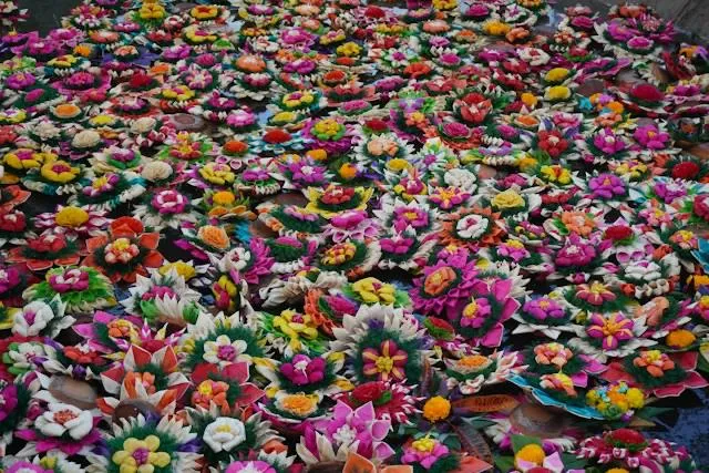 Dozzine di krathong colorati, cesti galleggianti di fiori, sull'acqua durante il festival Loy Krathong in Thailandia