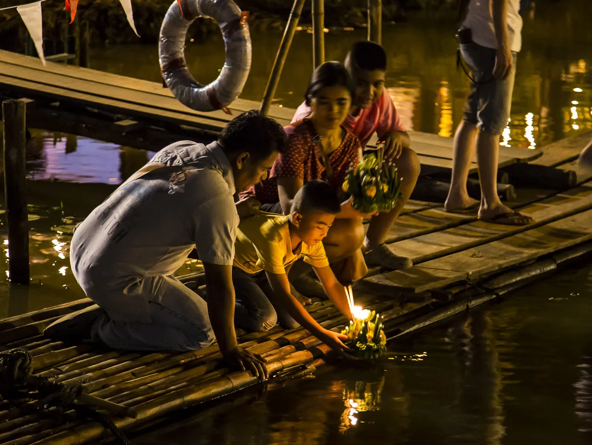 Un krathong lasciato galleggiare sul fiume Ping Una famiglia thailandese fa galleggiare un krathong con candela sul fiume Ping a Chiang Mai durante il festival Loy Krathong