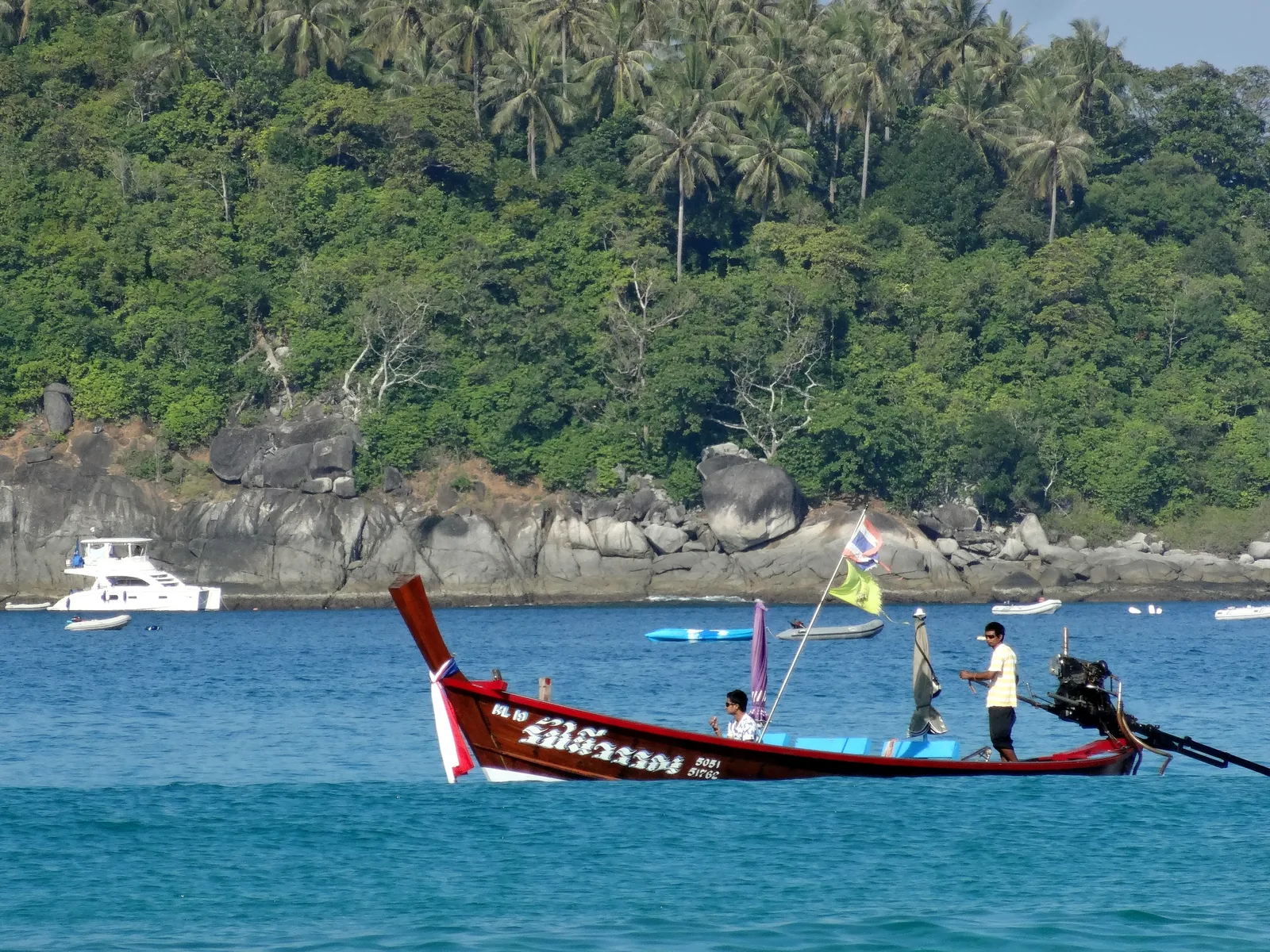 Longtail boat a Kata Beach, Phuket Barca longtail in mare turchese davanti alla costa di Kata a Phuket nella stagione secca del Mar delle Andamane