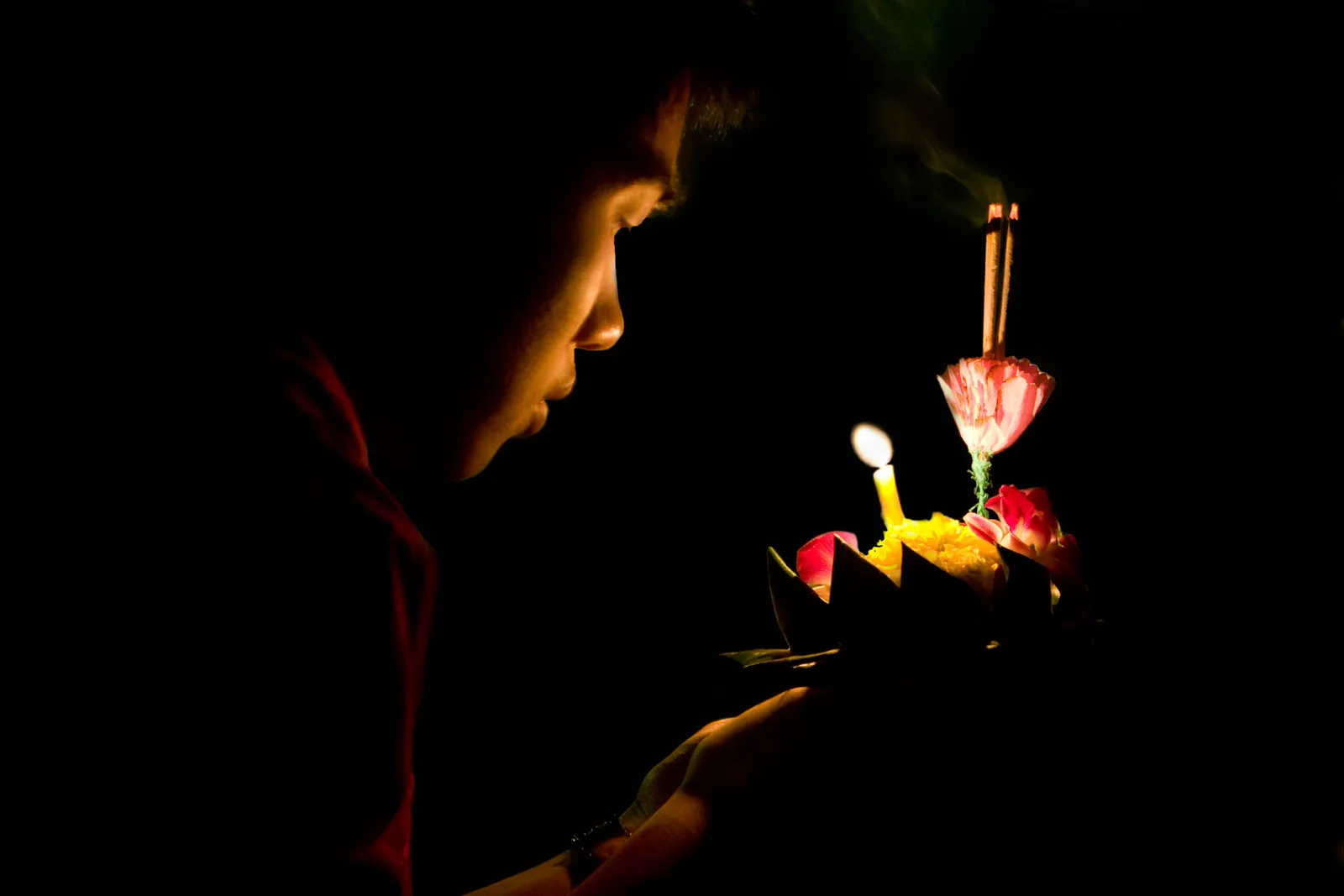 Un krathong acceso pronto per essere lanciato a Bangkok Una ragazza regge un krathong con candela e incenso accesi durante il festival Loy Krathong a Bangkok, Thailandia