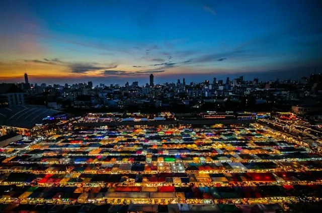 Vista aerea di un mercato notturno di Bangkok al tramonto, con tende colorate illuminate