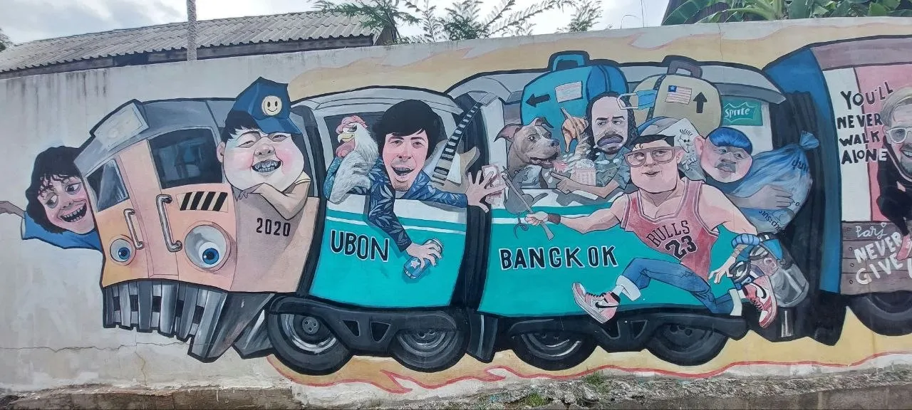 Un murale di street art ad Ubon Ratchathani con un treno colorato che collega Ubon a Bangkok, pieno di personaggi stilizzati tra i vagoni