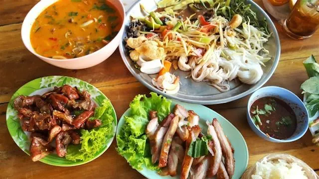 Piatti thailandesi preparati durante un corso di cucina Tavolata di piatti thailandesi appena preparati: zuppa tom yum, insalata di papaya, carne alla griglia e riso