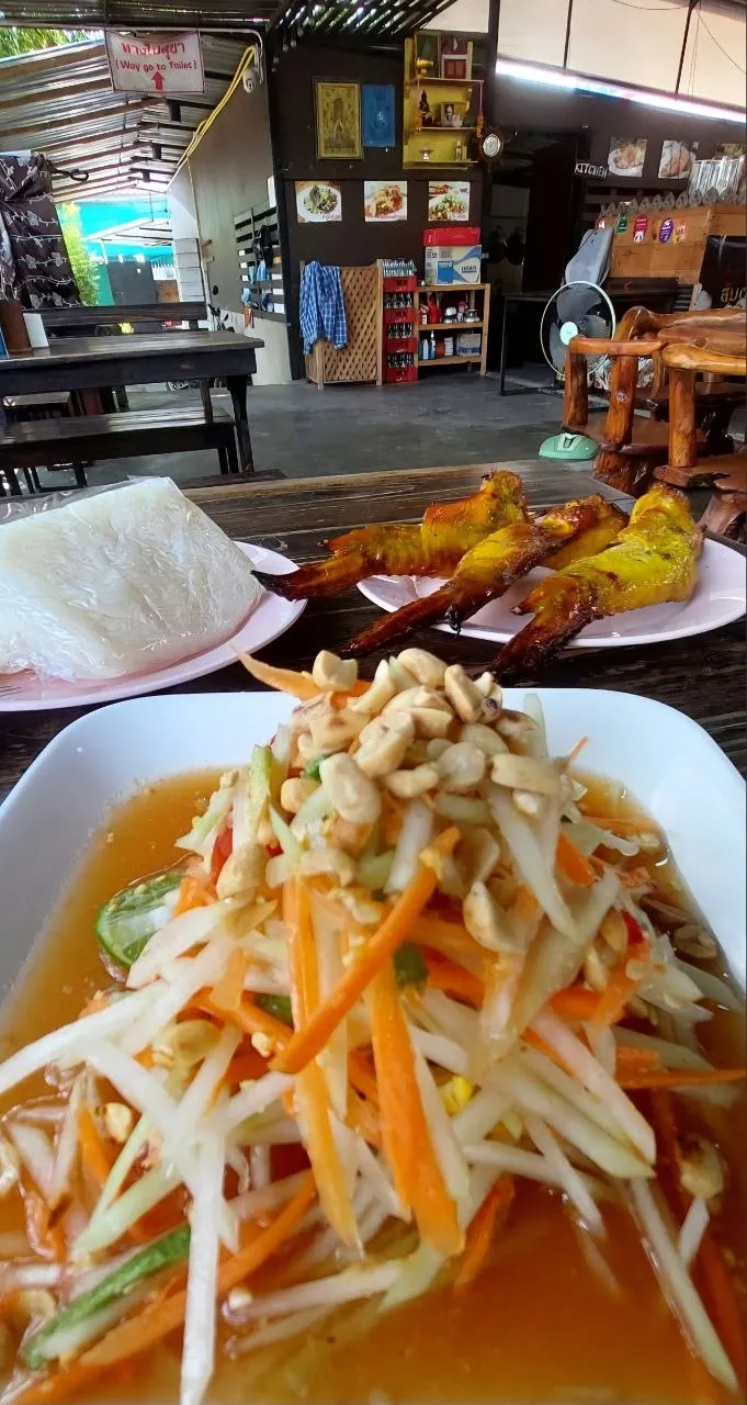 Un pasto tipico dell'Isan su un tavolo di legno: som tam (insalata di papaya verde), gai yang (pollo alla griglia) e riso glutinoso (sticky rice) avvolto in un sacchetto di plastica, in un ristorante del nord-est della Thailandia