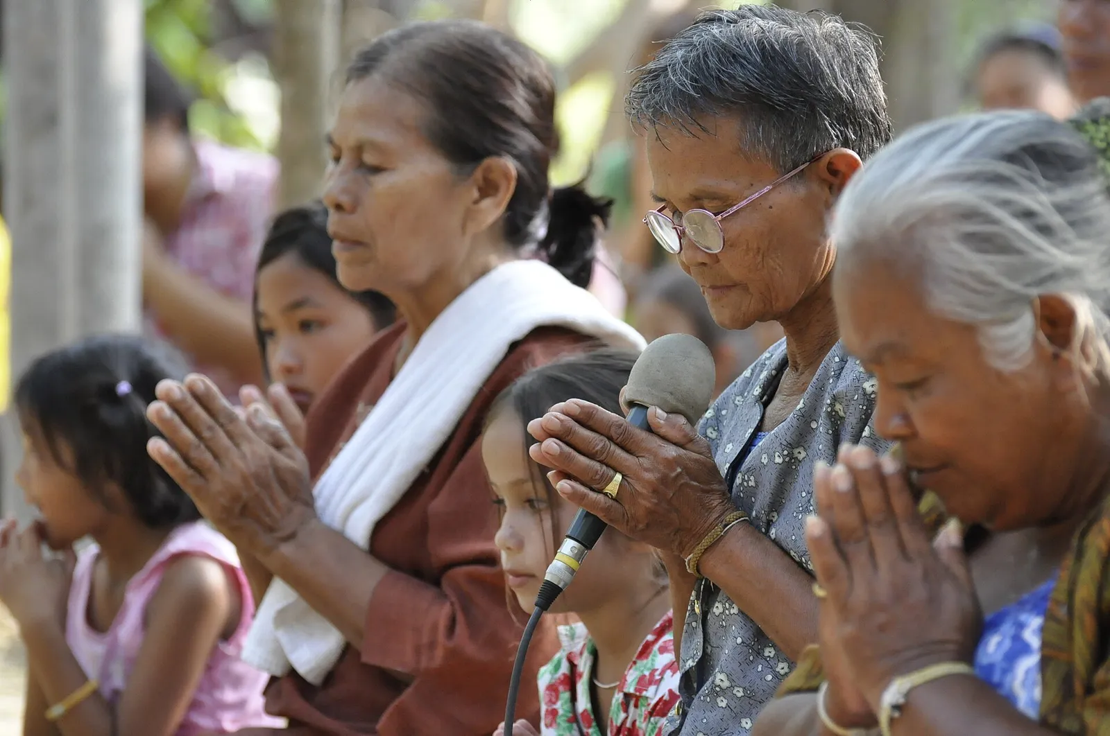 Gruppo di persone thailandesi con le mani giunte davanti al petto in segno di saluto e rispetto