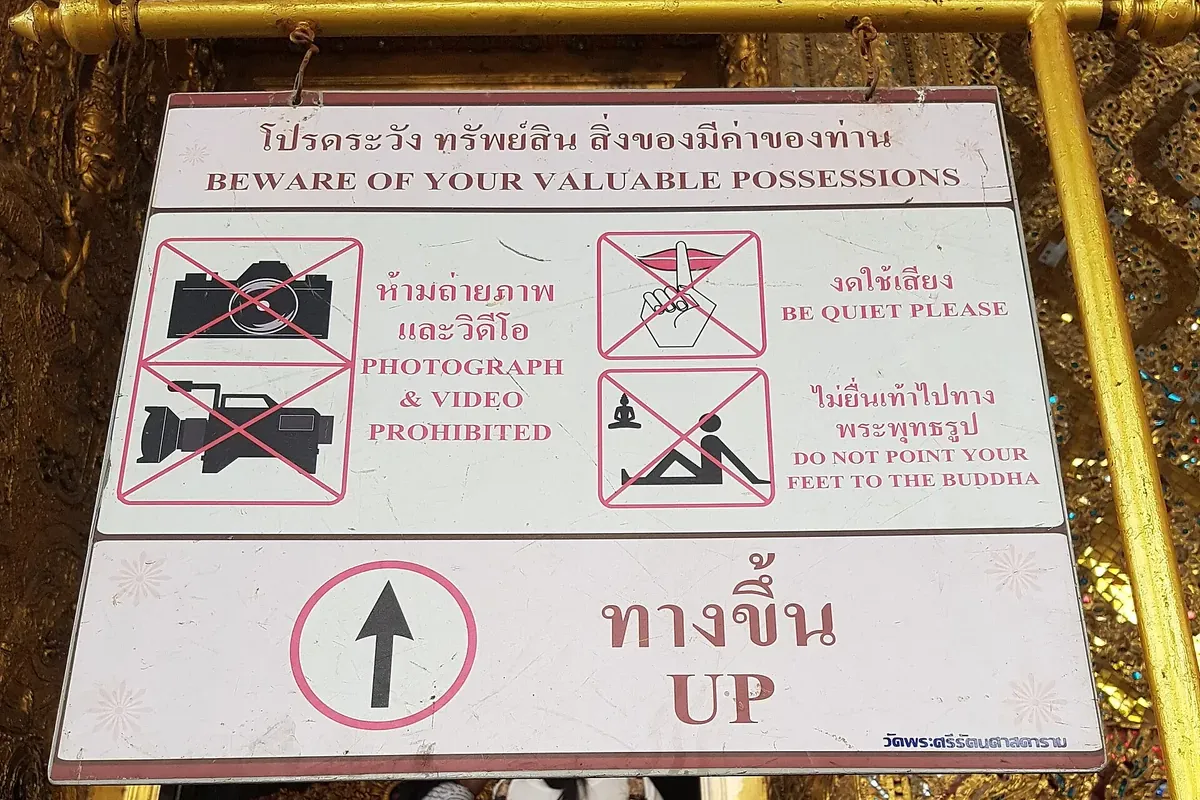 Cartello bilingue in alfabeto thailandese e inglese con le regole di comportamento in un tempio di Bangkok