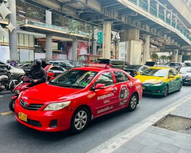 Taxi nel traffico di Bangkok Taxi rosso nel traffico di Bangkok sotto la linea sopraelevata della BTS Skytrain