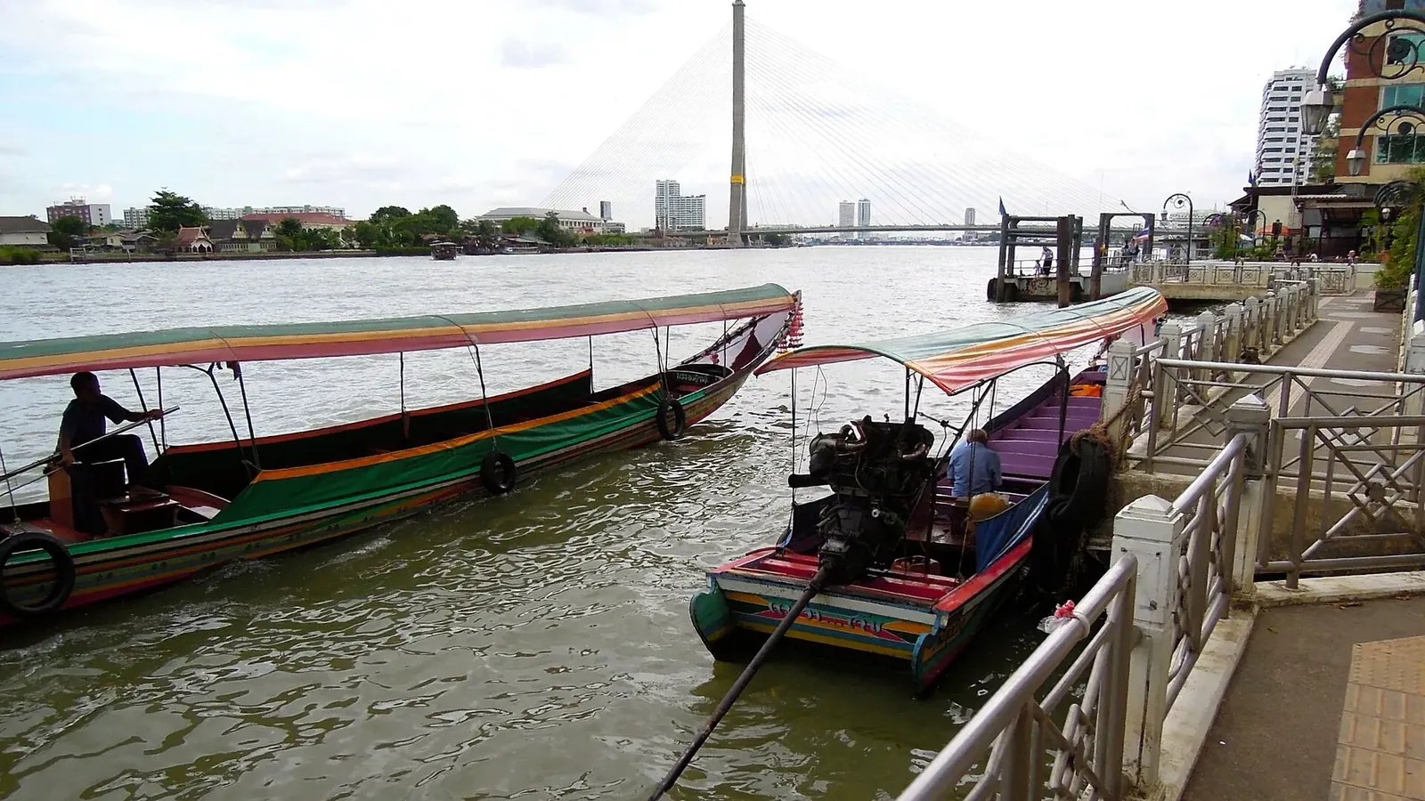 Longtail boat sul Chao Phraya a Bangkok Barche longtail sul fiume Chao Phraya a Bangkok, con la riva e i grattacieli sullo sfondo